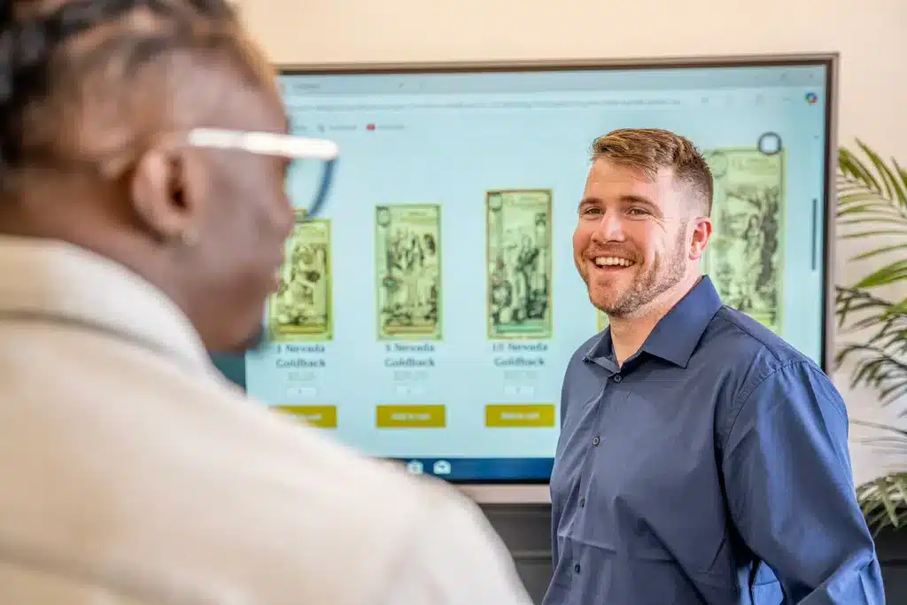 A customer viewing Goldback denominations on a display, showing real-world Goldback use